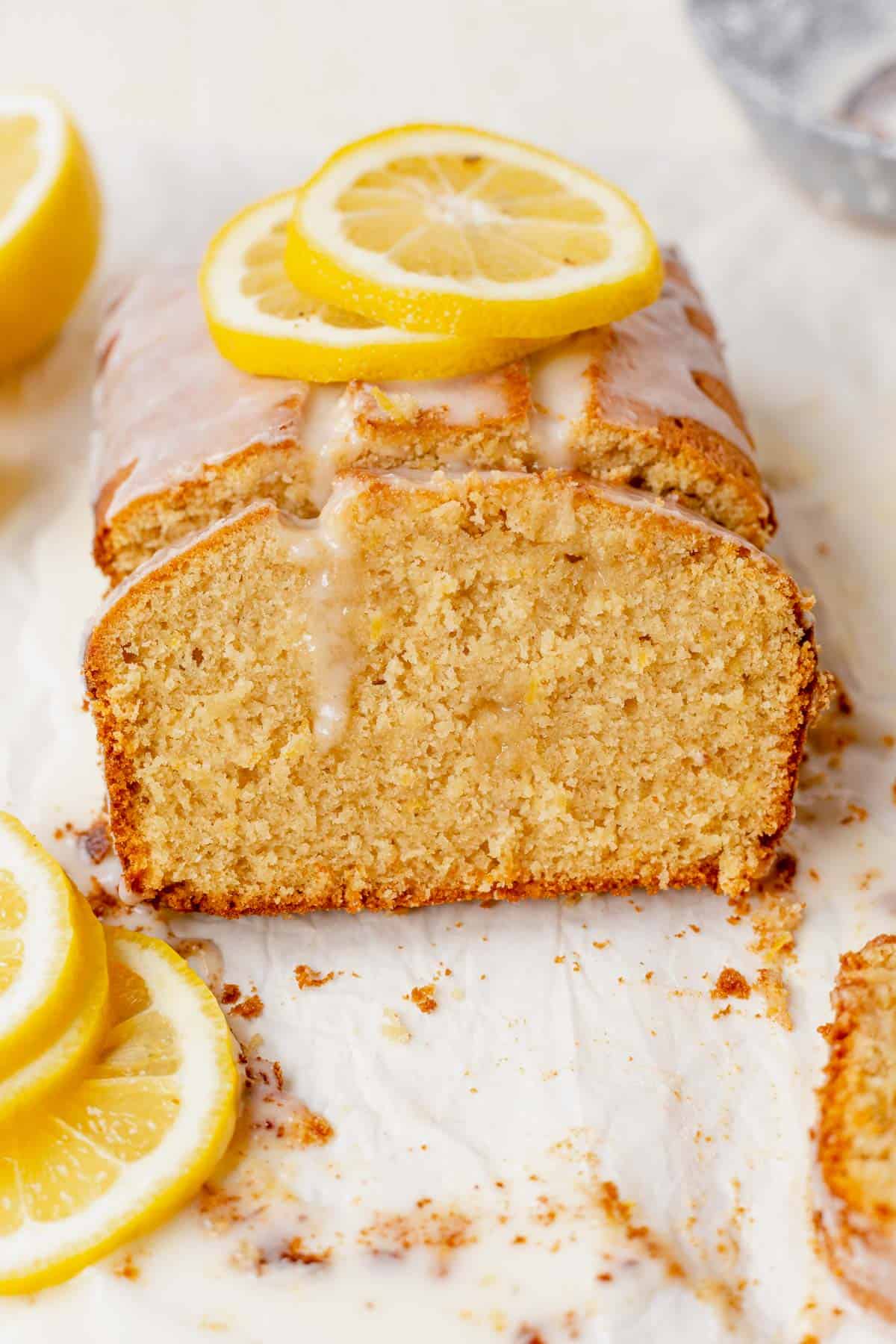 a piece of gluten-free lemon drizzle cake leaning against the loaf