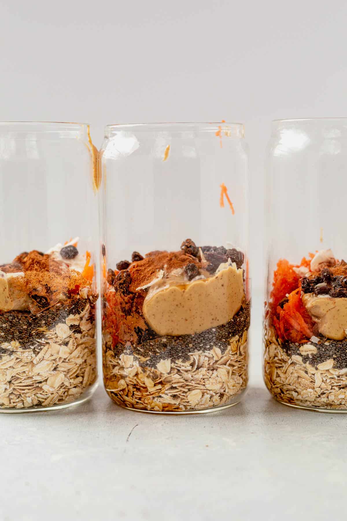 oats, carrots, almond butter, raisins, and spices in glass jars