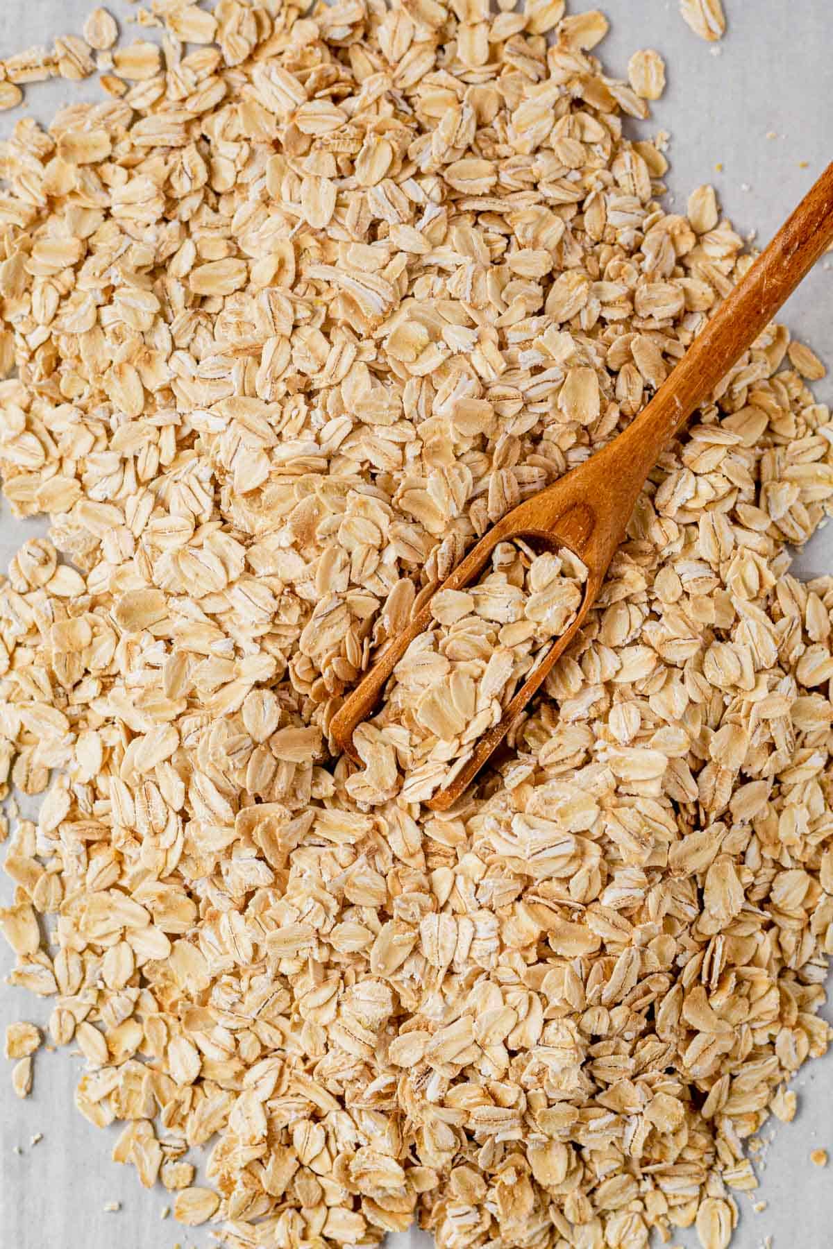 a pile of rolled oats on a countertop with a wooden spoon