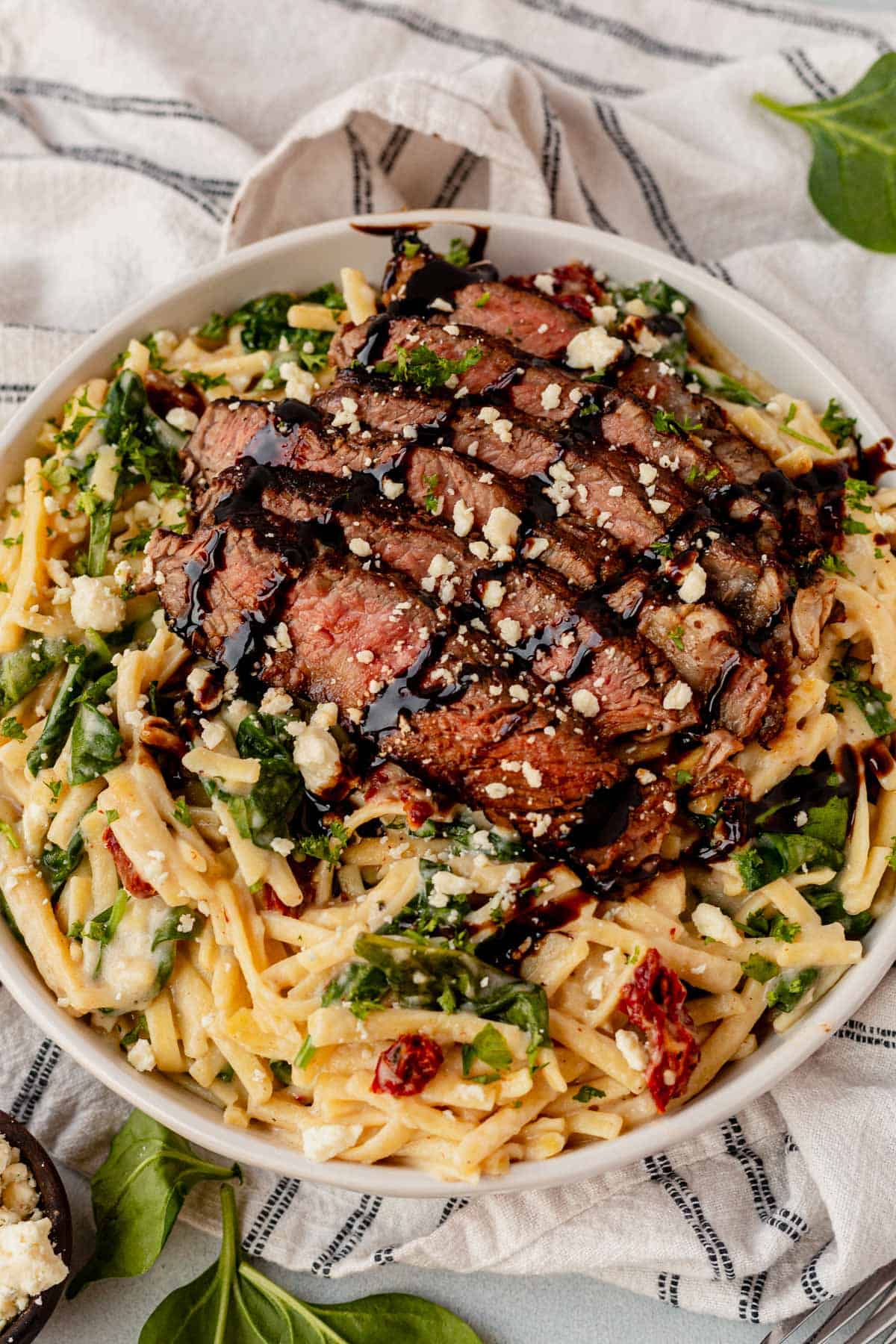 steak pasta in a bowl with blue cheese and balsamic glaze