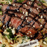 steak pasta dish drizzled with balsamic resting on a white dinner plate