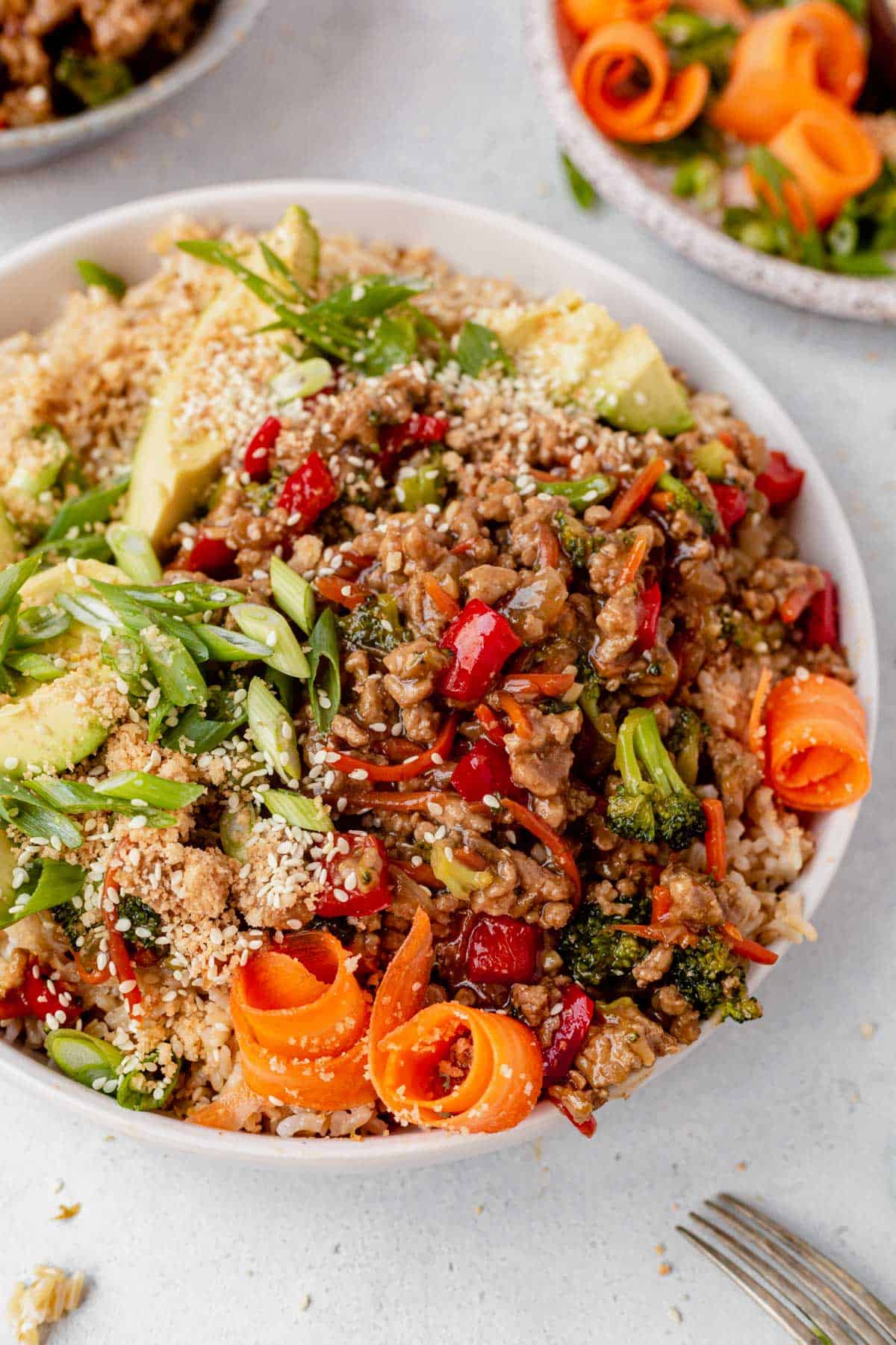 a bowl of rice with ground turkey, veggies and teriyaki sauce