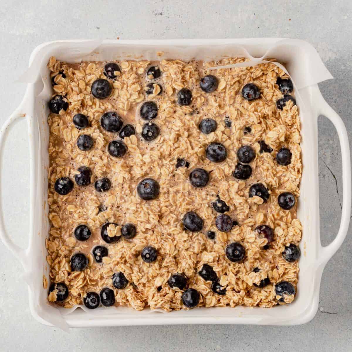 raw ingredients for healthy blueberry baked oatmeal combined and poured into 9x9 baking dish
