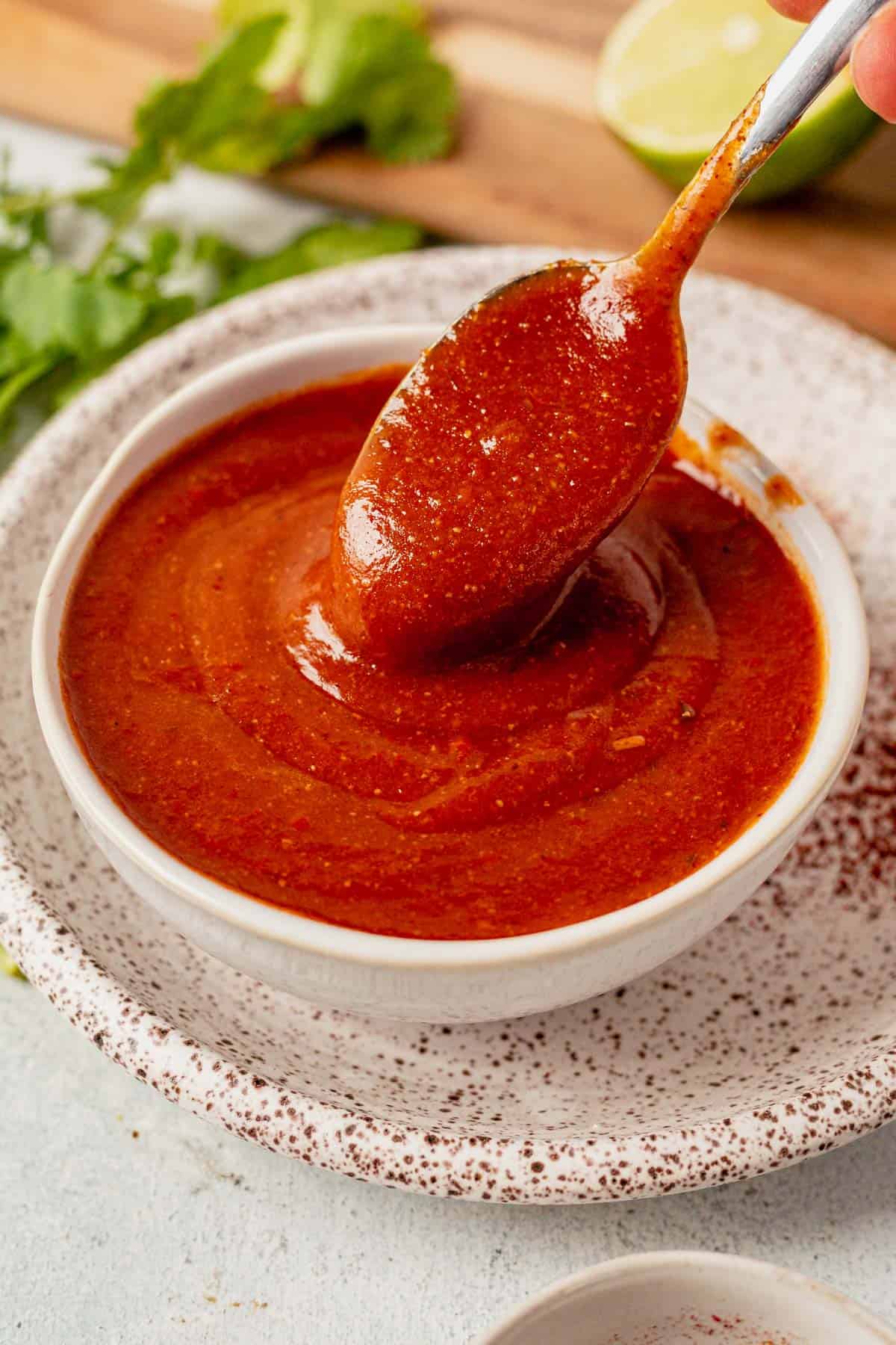 a spoonful of gluten free enchilada sauce coming out of a bowl
