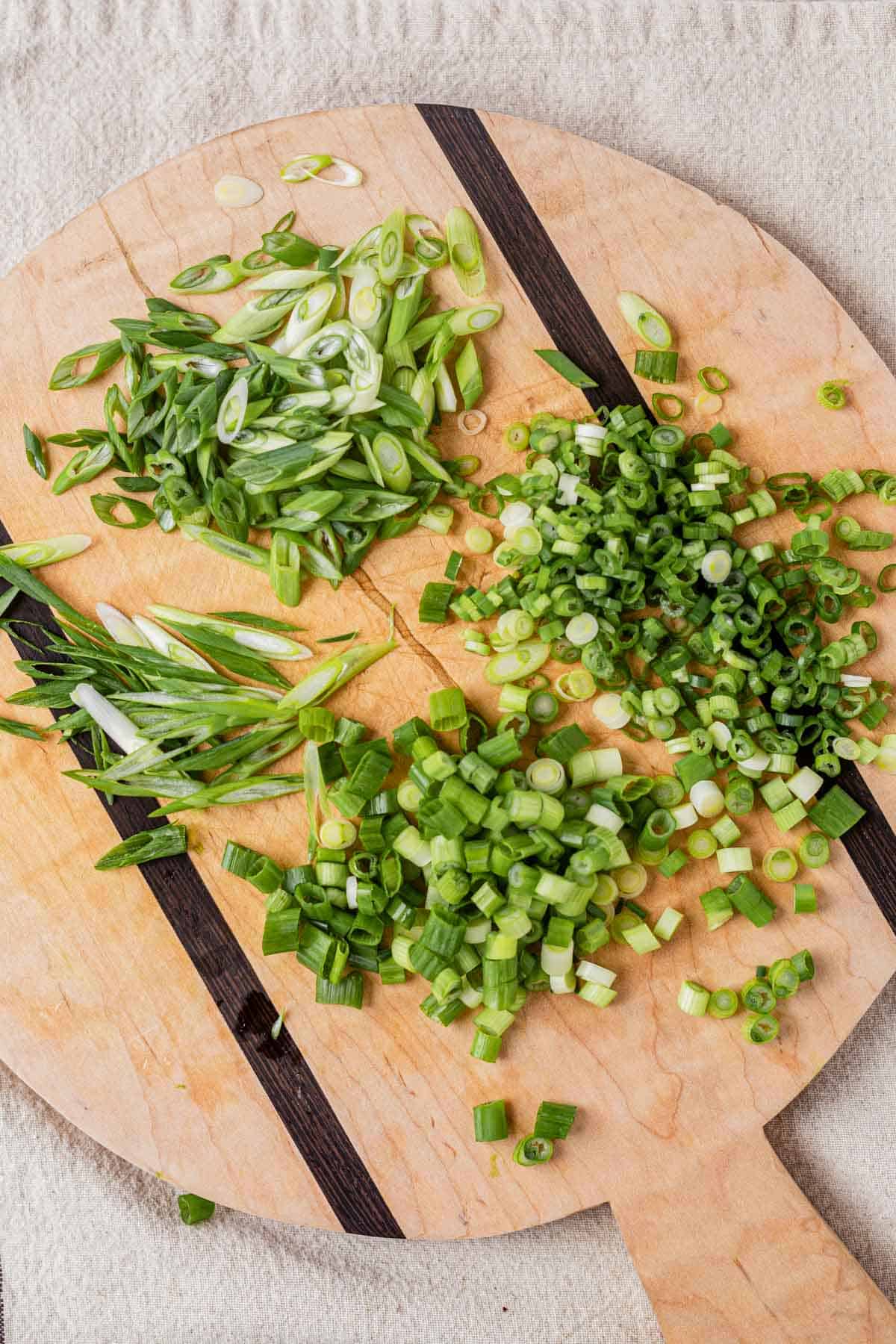 green onions on a cutting board cut up 3 different ways