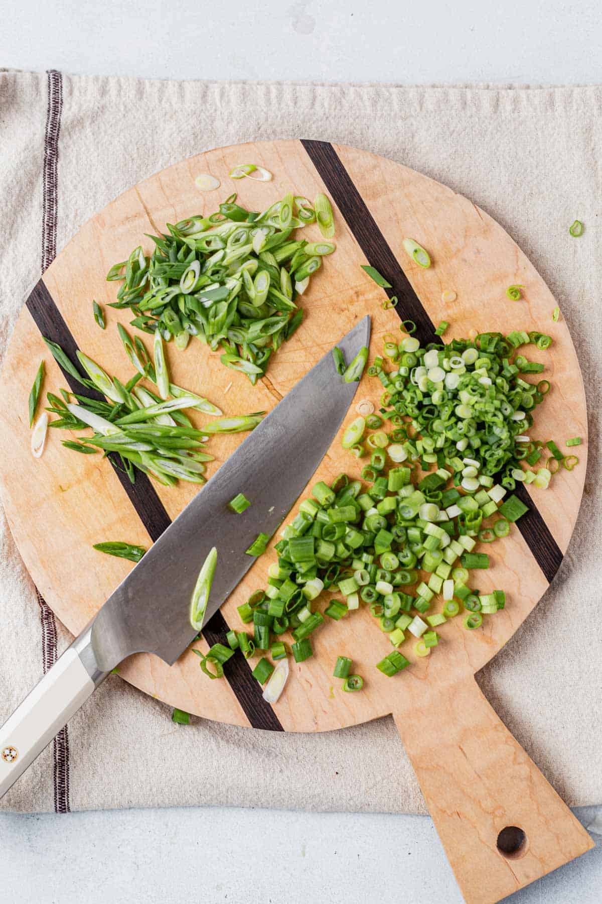 slice green onions on a cutting board with a knife
