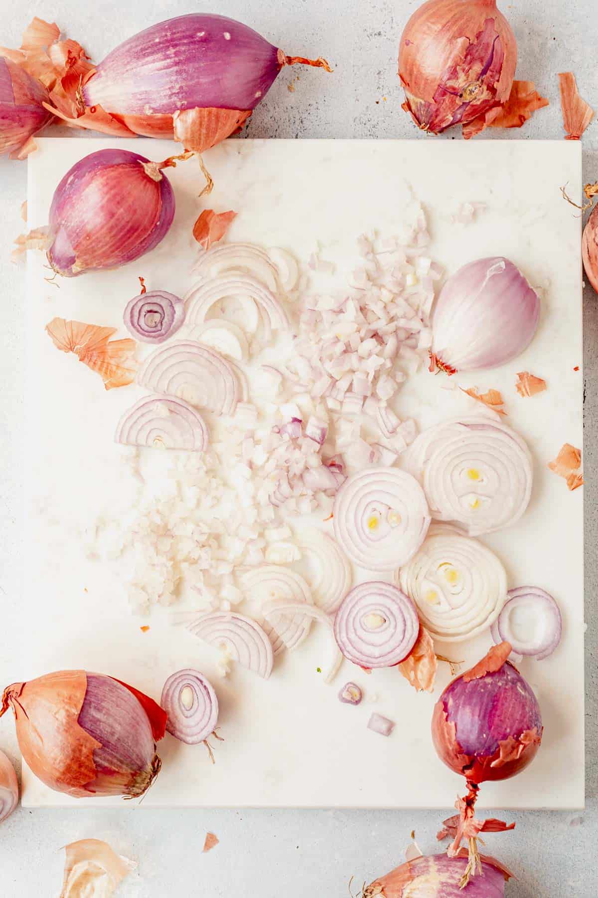 whole shallots, diced shallots, and sliced shallots on a cutting board