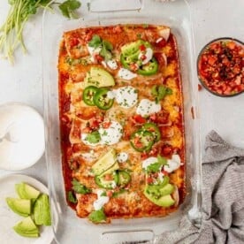 shredded beef enchiladas in a dish with toppings