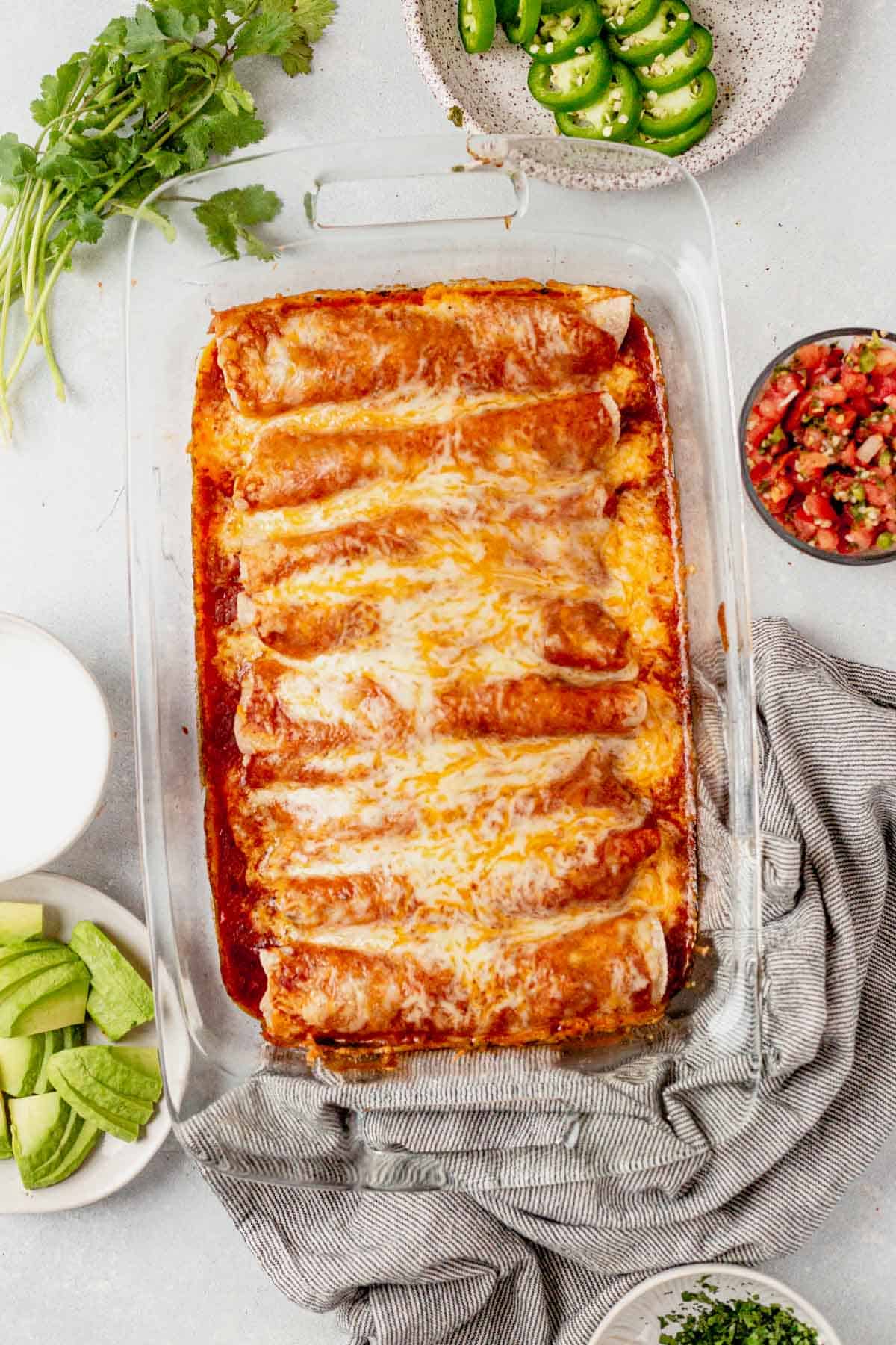 beef enchiladas in a pan with homemade sauce and cheese