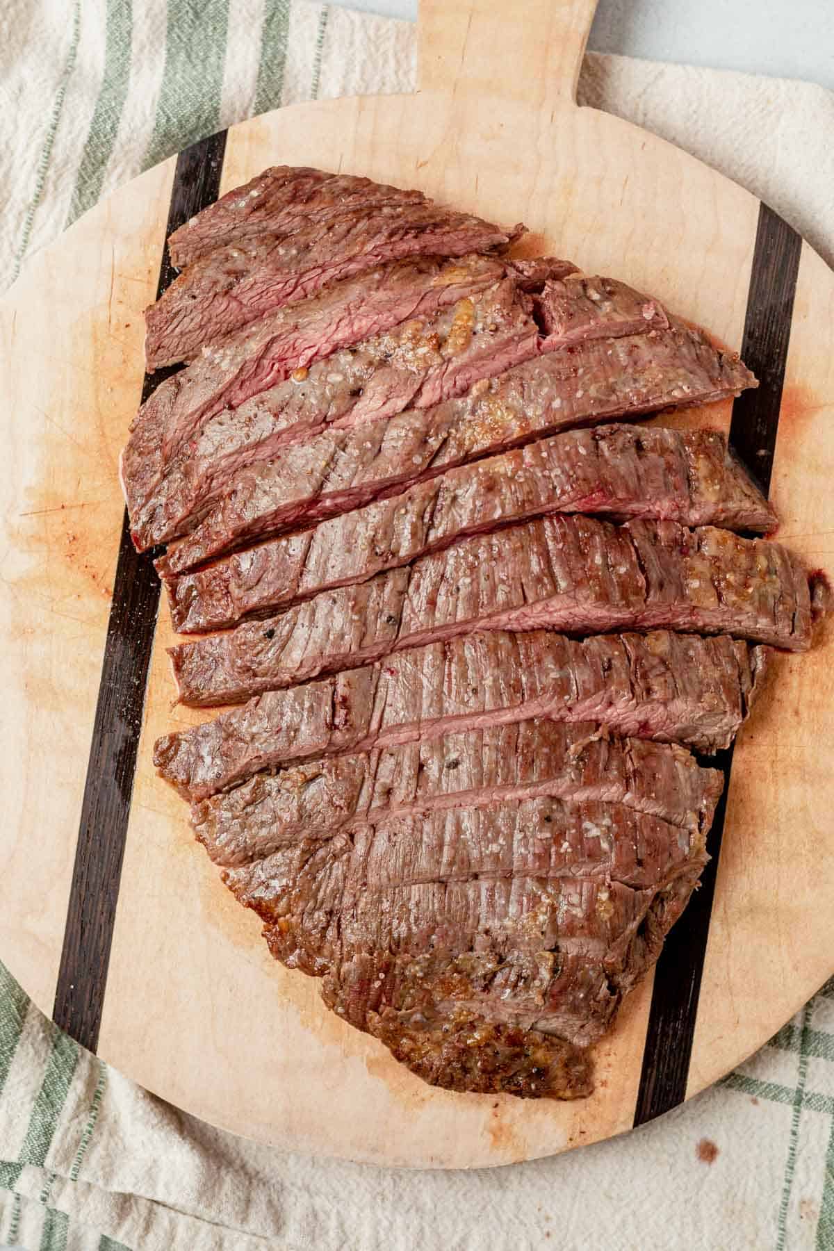 thinly sliced cooked flank steak resting on a cutting board