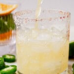 pouring a spicy skinny margarita into a glass of ice