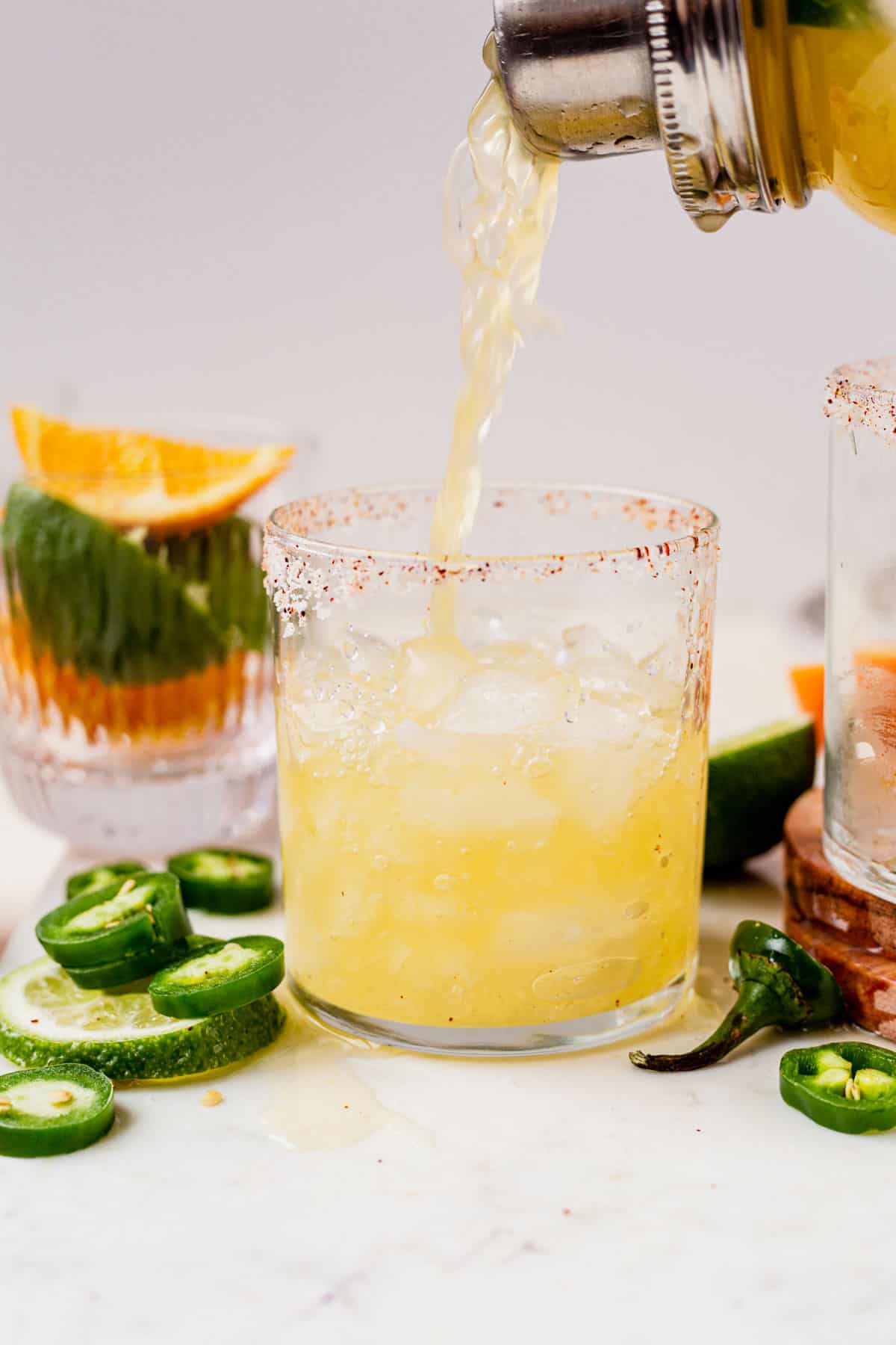 pouring a skinny spicy margarita from a cocktail shaker into a glass