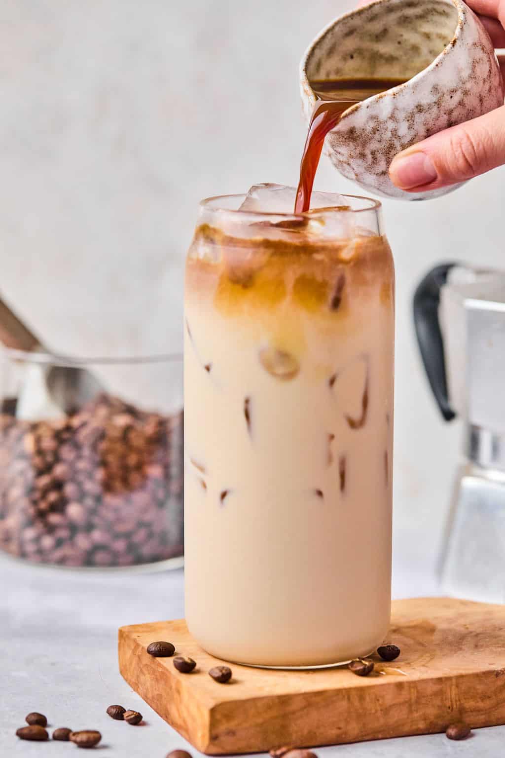 pouring a shot of espresso into an iced caramel latte.