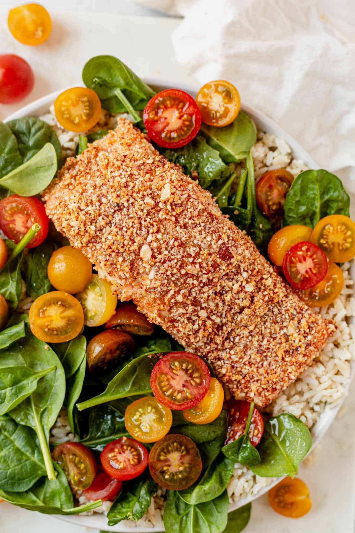almond crusted salmon on a salad with tomatoes