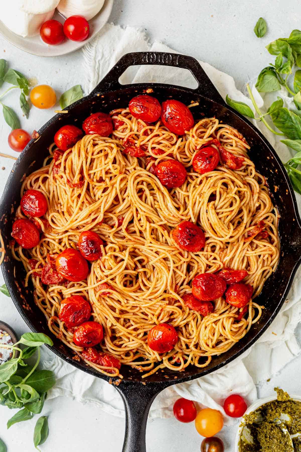 cooked pasta in a skillet with burst tomatoes