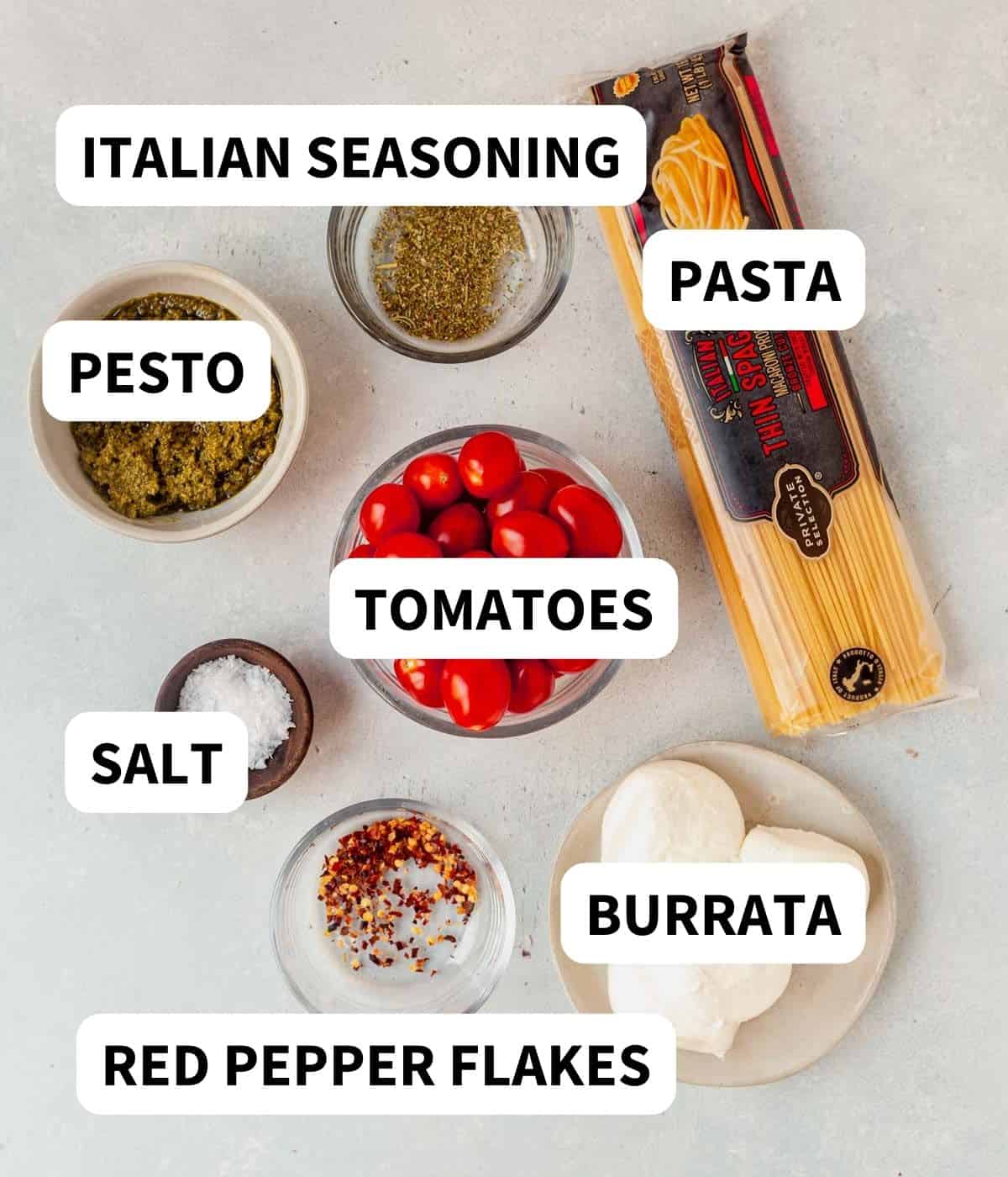 burrata, pasta, tomatoes, pesto and spices on a countertop