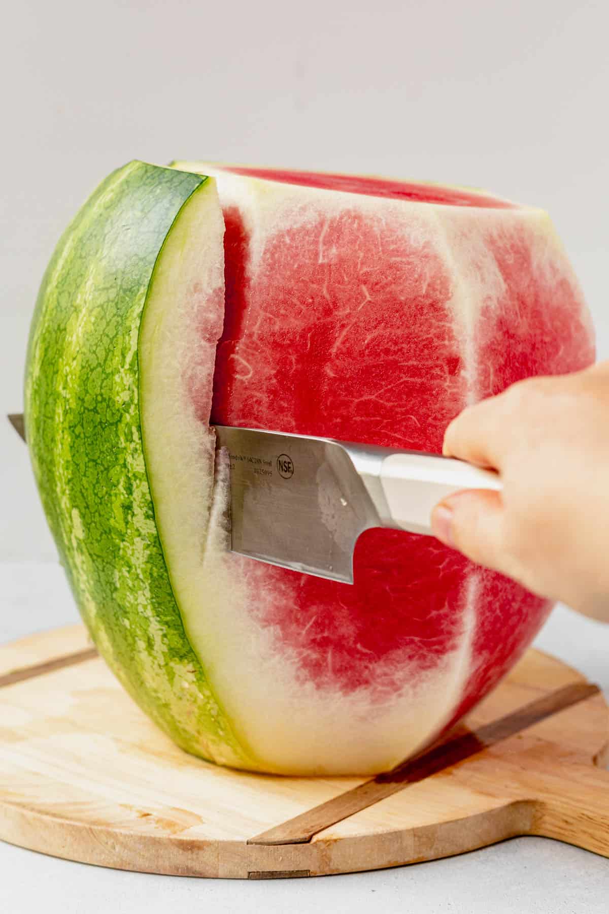 cutting the green rind off of a watermelon