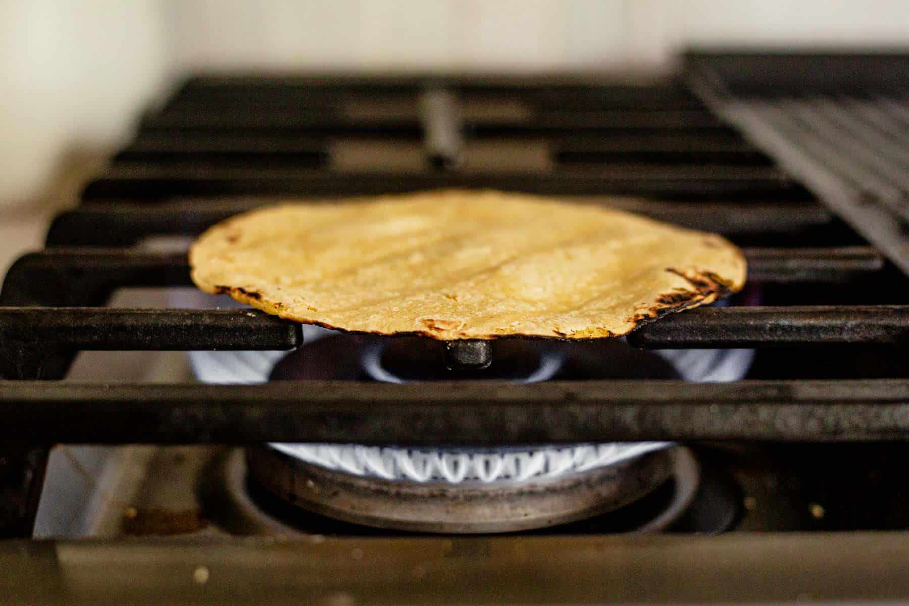 tortilla shell warming over an open flame on gas stove