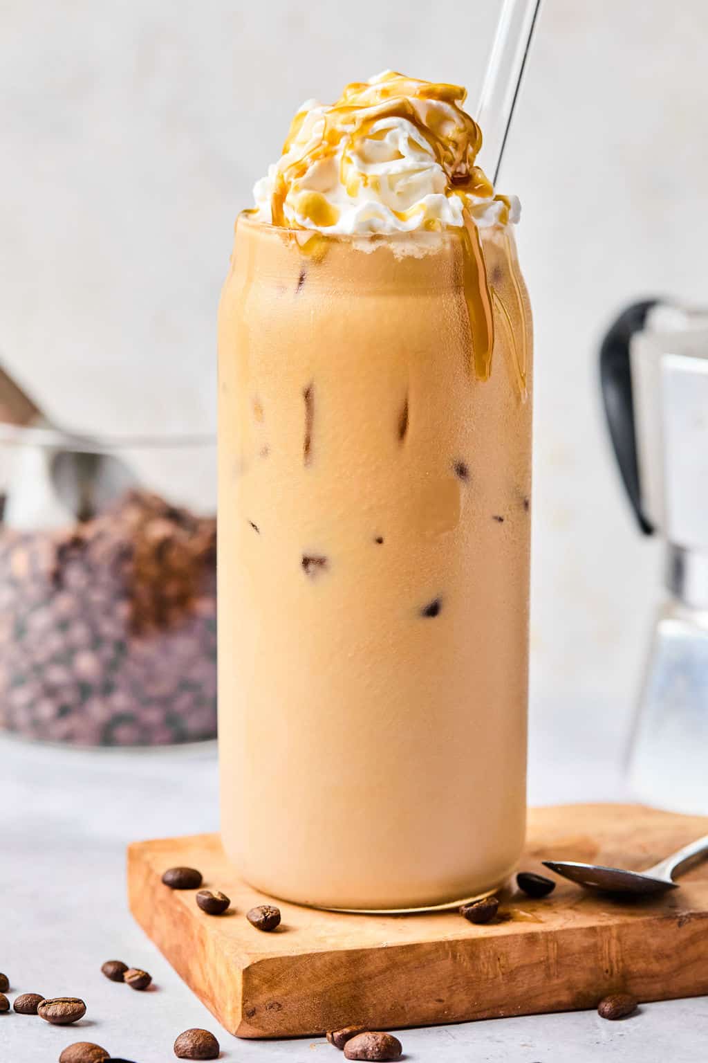 iced caramel latte in a glass with whipped cream and caramel sauce on top.