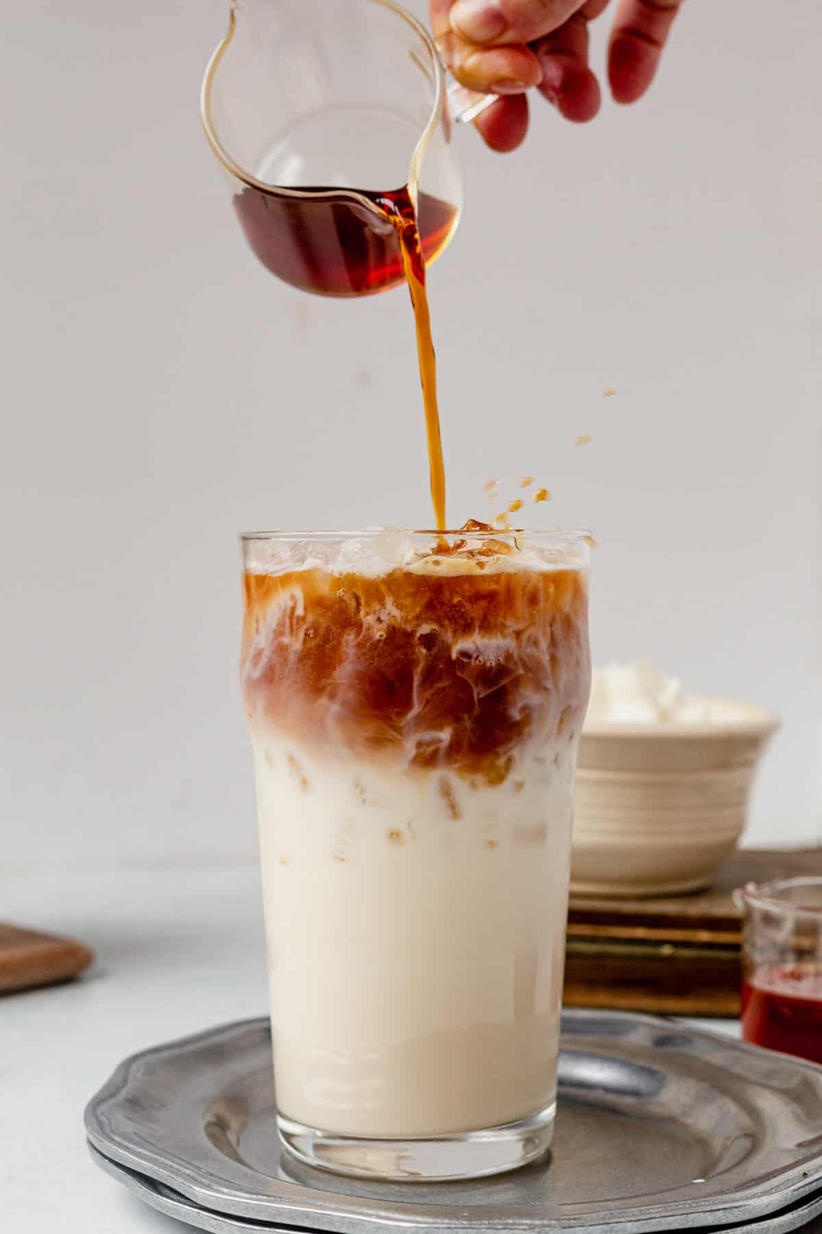 pouring espresso into an iced caramel latte