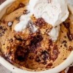 close up of chocolate chip mug cake dug into with a vanilla ice cream scoop on top