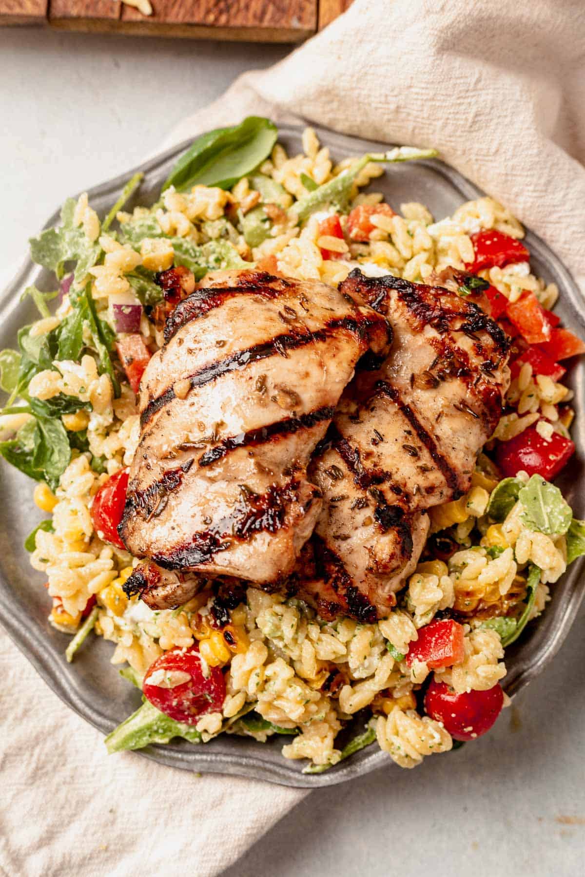 grilled chicken thighs on top of orzo pasta salad