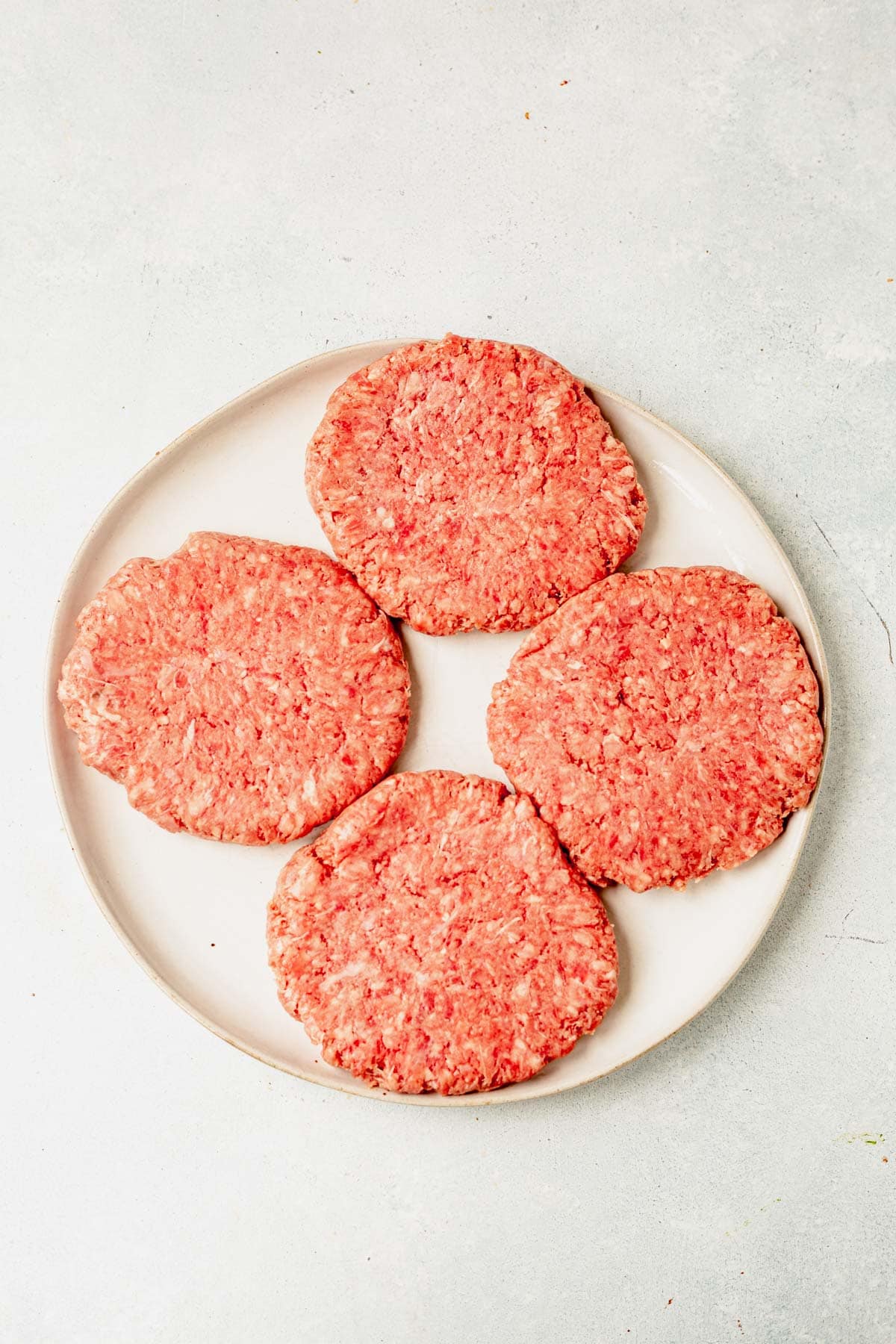 4 raw burger patties on a plate