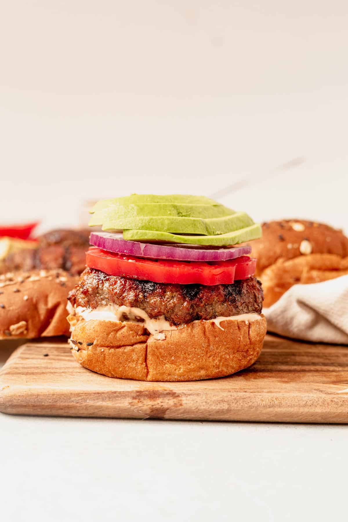 grilled burger with avocado and tomato on top