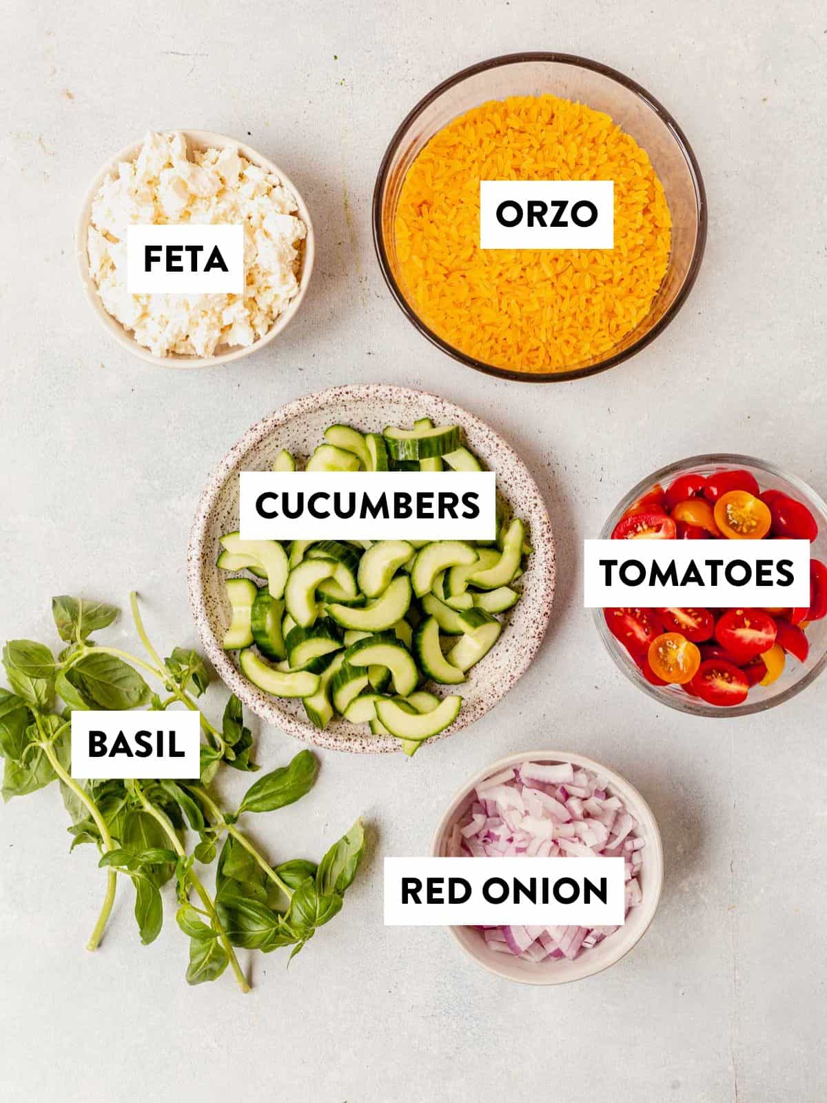 ingredients for salad portion of lemon basil orzo salad laid out on a counter and labeled