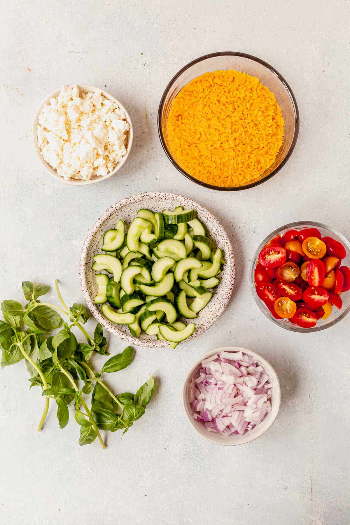 ingredients for lemon orzo pasta salad in separate bowls on a counter