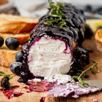a log of blueberry goat cheese on a cutting board