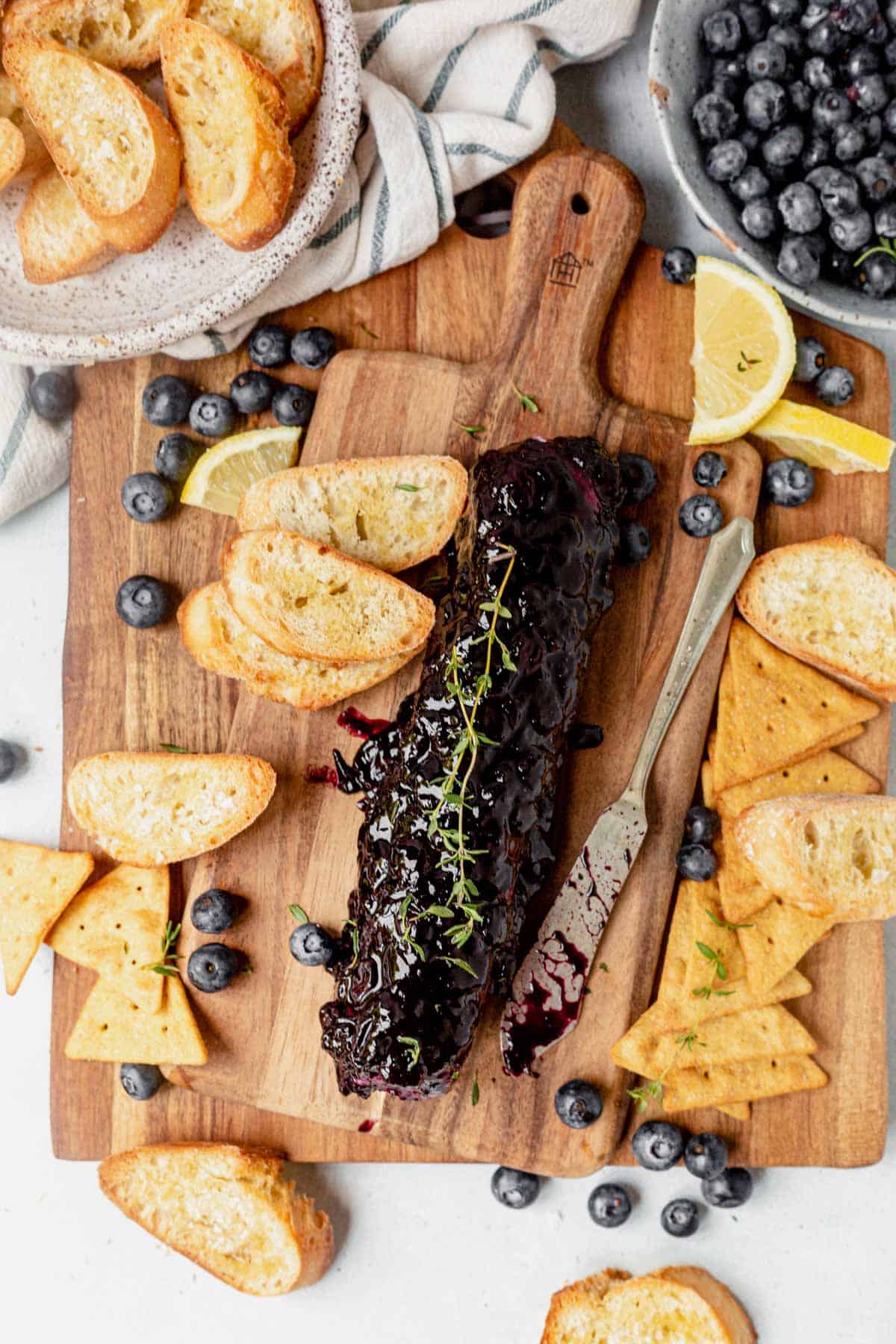 a log of blueberry goat cheese and crackers on a board