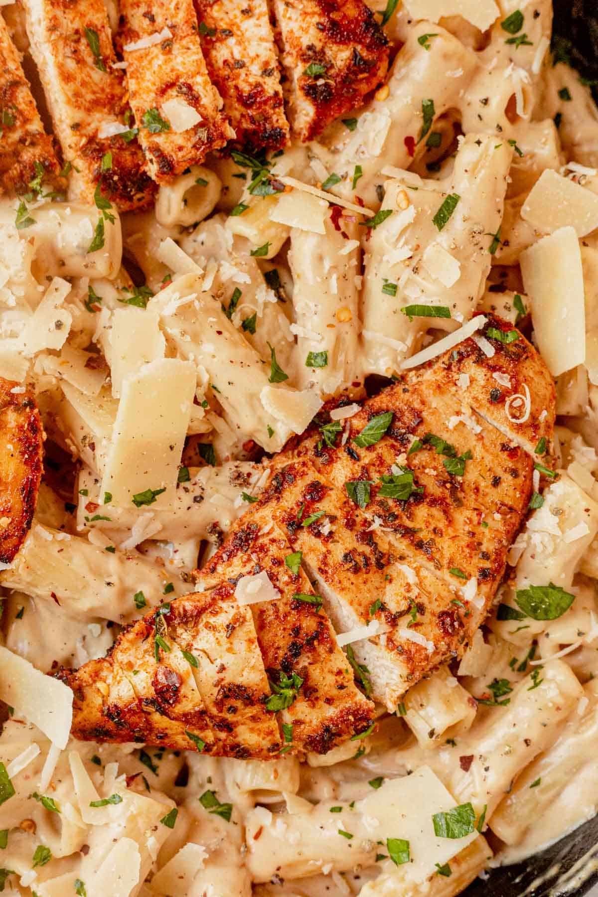 sliced chicken breast on top of cheesy pasta
