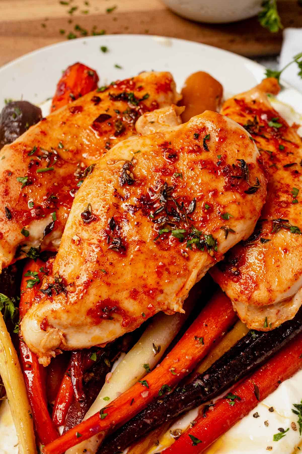 baked chicken breast on top of roasted carrots
