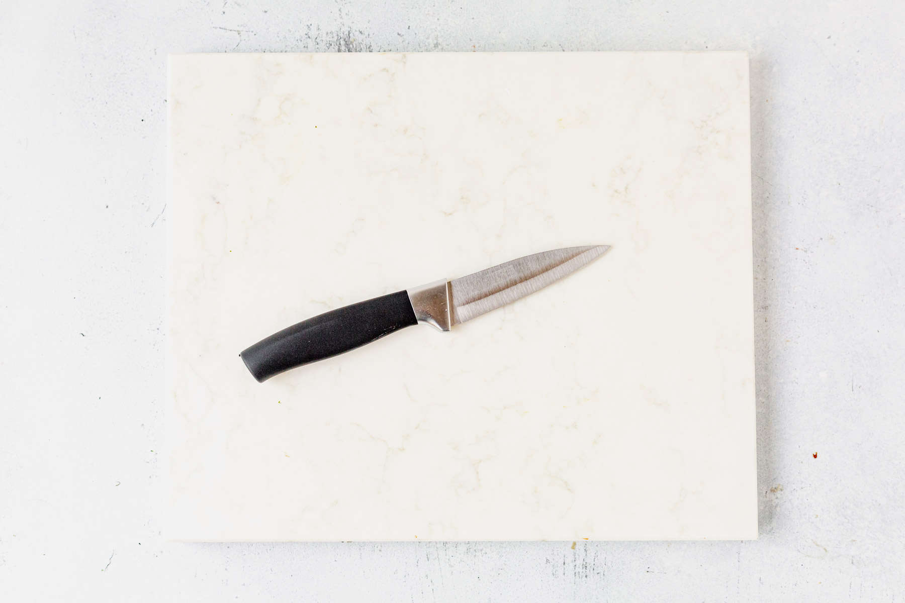 a cutting board and pairing knife on a countertop