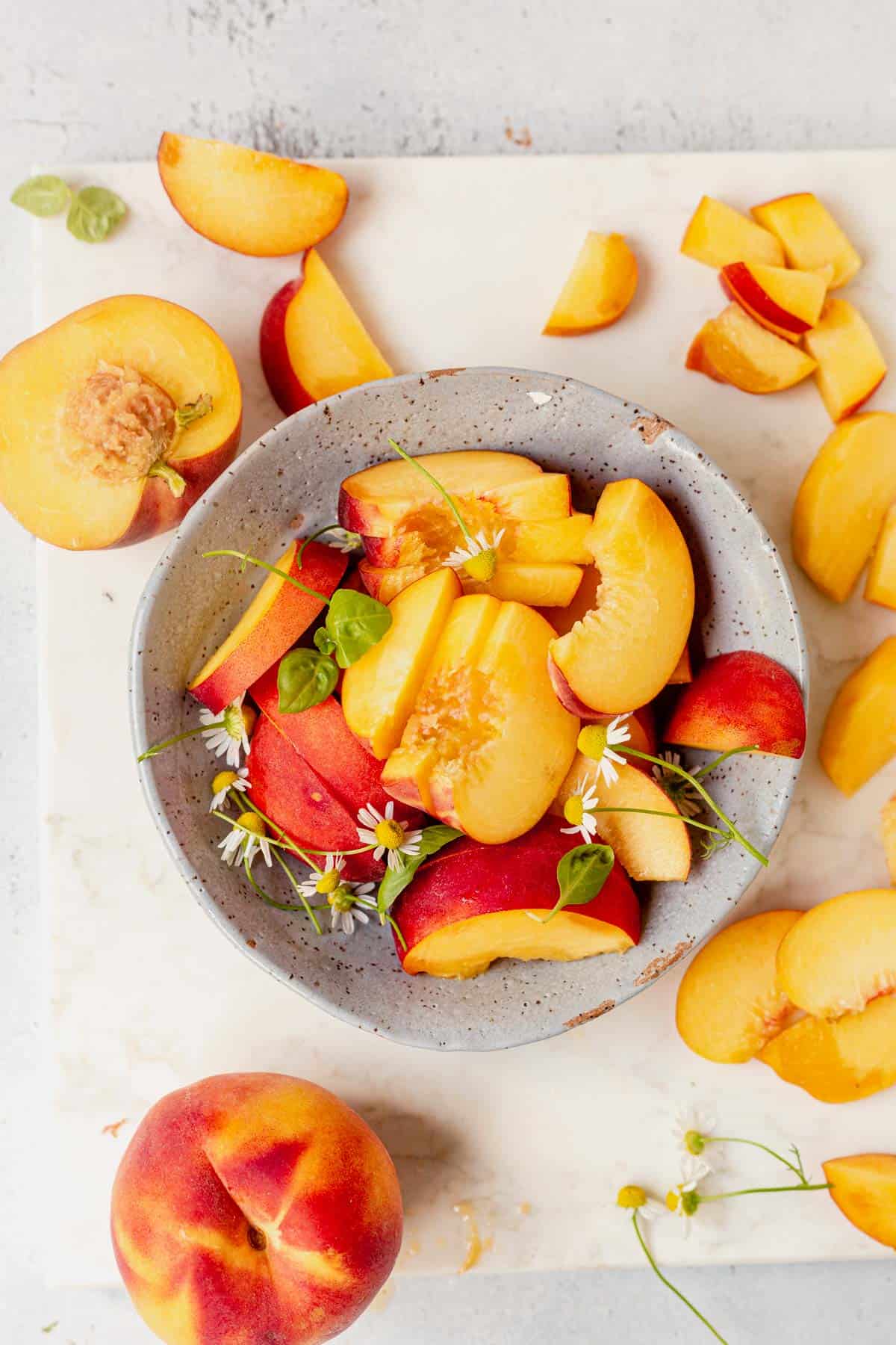 a bowl of sliced peaches on a cutting board