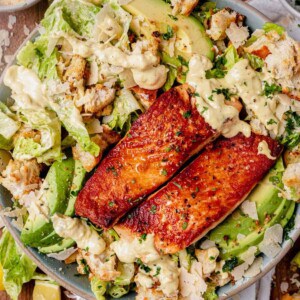 a bowl of salmon caesar salad with croutons