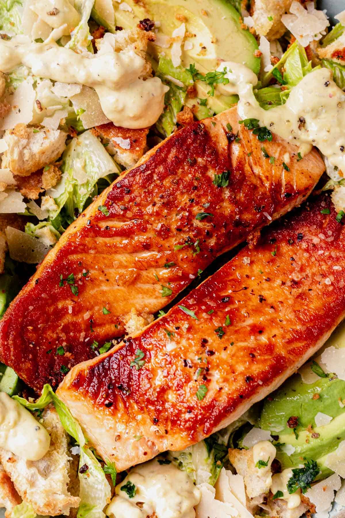 two seared salmon filets on top of caesar salad