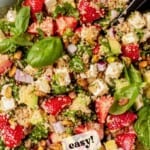 strawberry quinoa feta salad in a bowl next to spinach and lemon