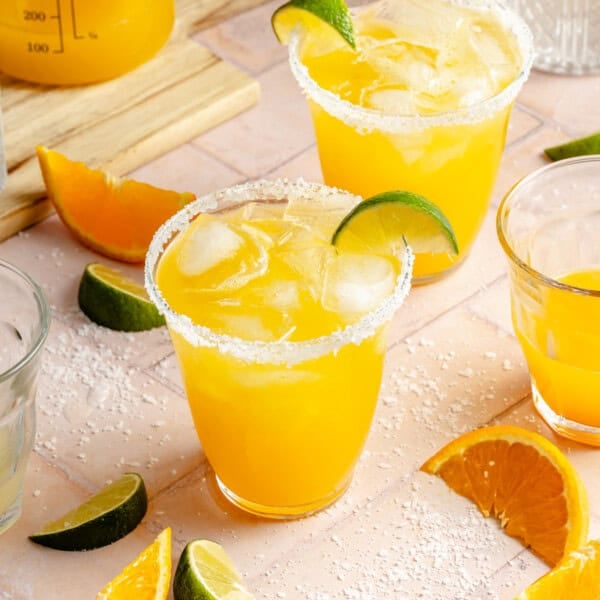 mango margarita recipe on the rocks with a salt rim and a lime wedge.
