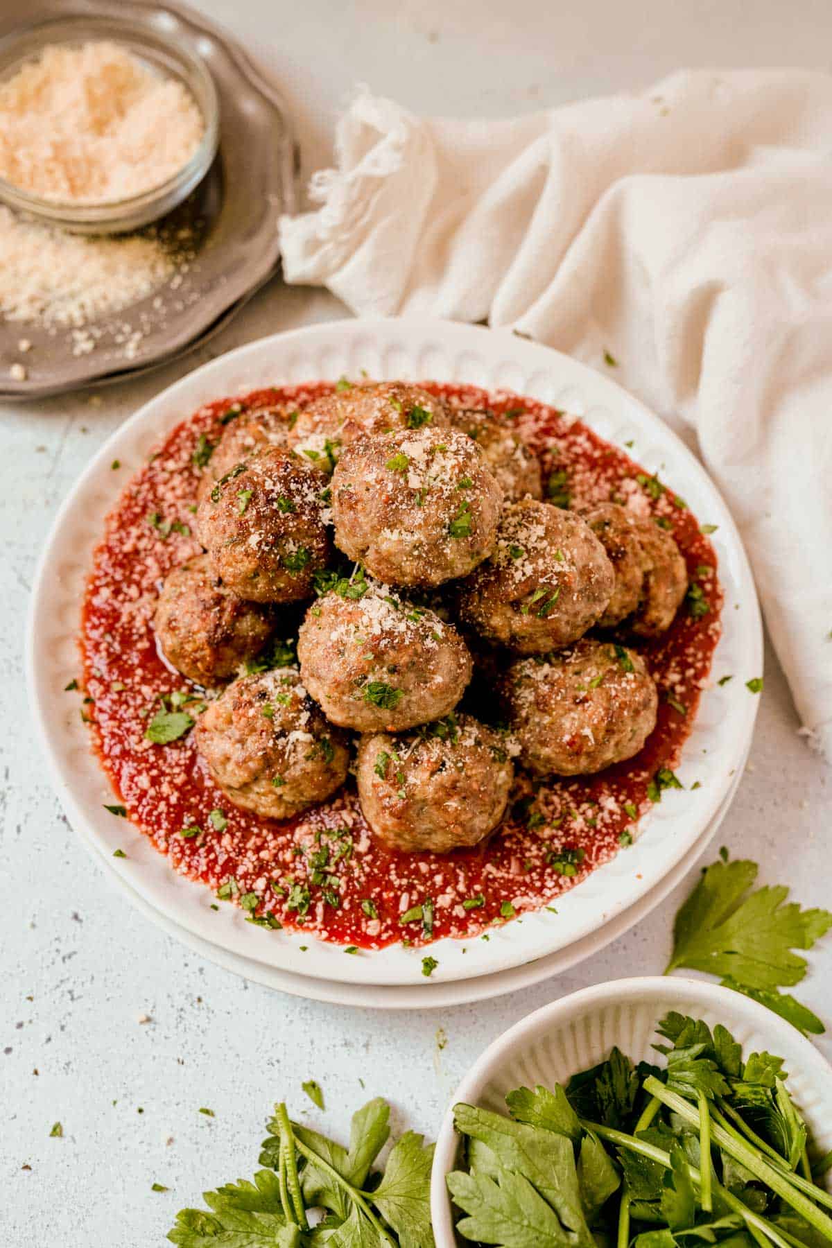 a plate of baked meatballs with parsley and parmesan cheese