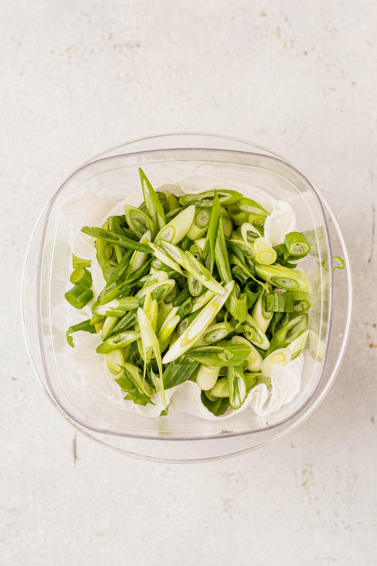 chopped green onion stored in a container with paper towels