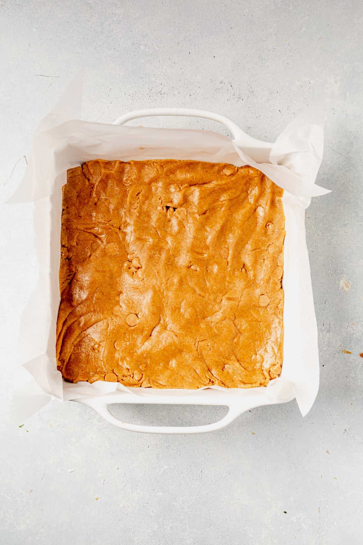 peanut butter cookie dough pressed into a square baking dish.