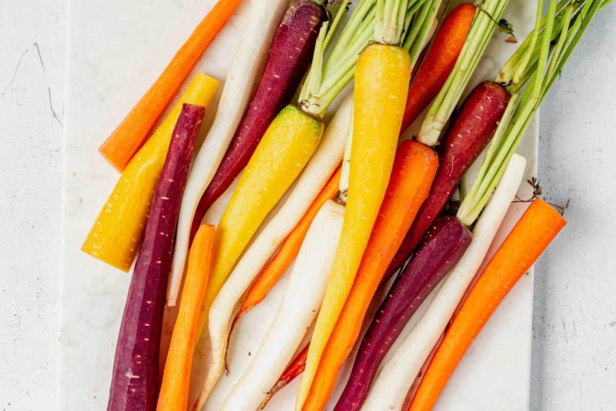 peeled rainbow carrots on a cutting board