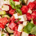 watermelon basil salad ingredients tossed together in a wooden bowl