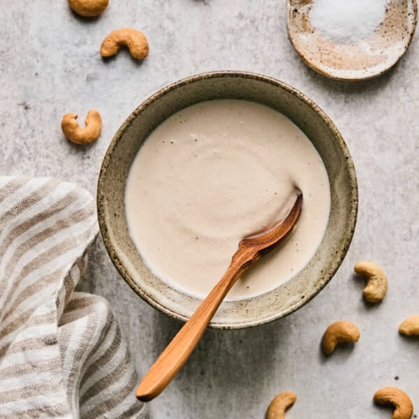 cashew cream recipe in a bowl with a wooden spoon.