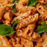 plate of creamy arrabbiata pasta garnished with fresh basil leaves.