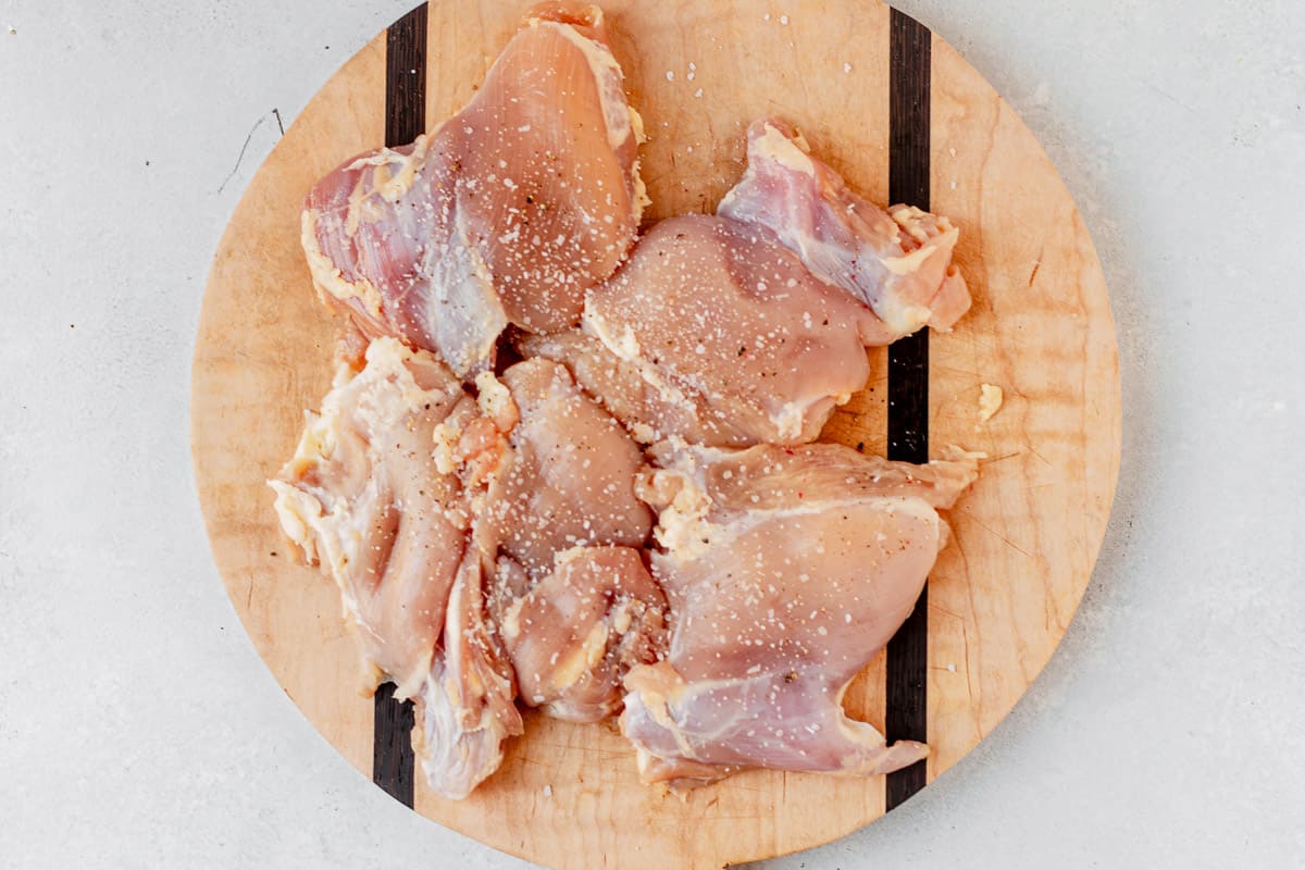 raw chicken thighs seasoned on a cutting board