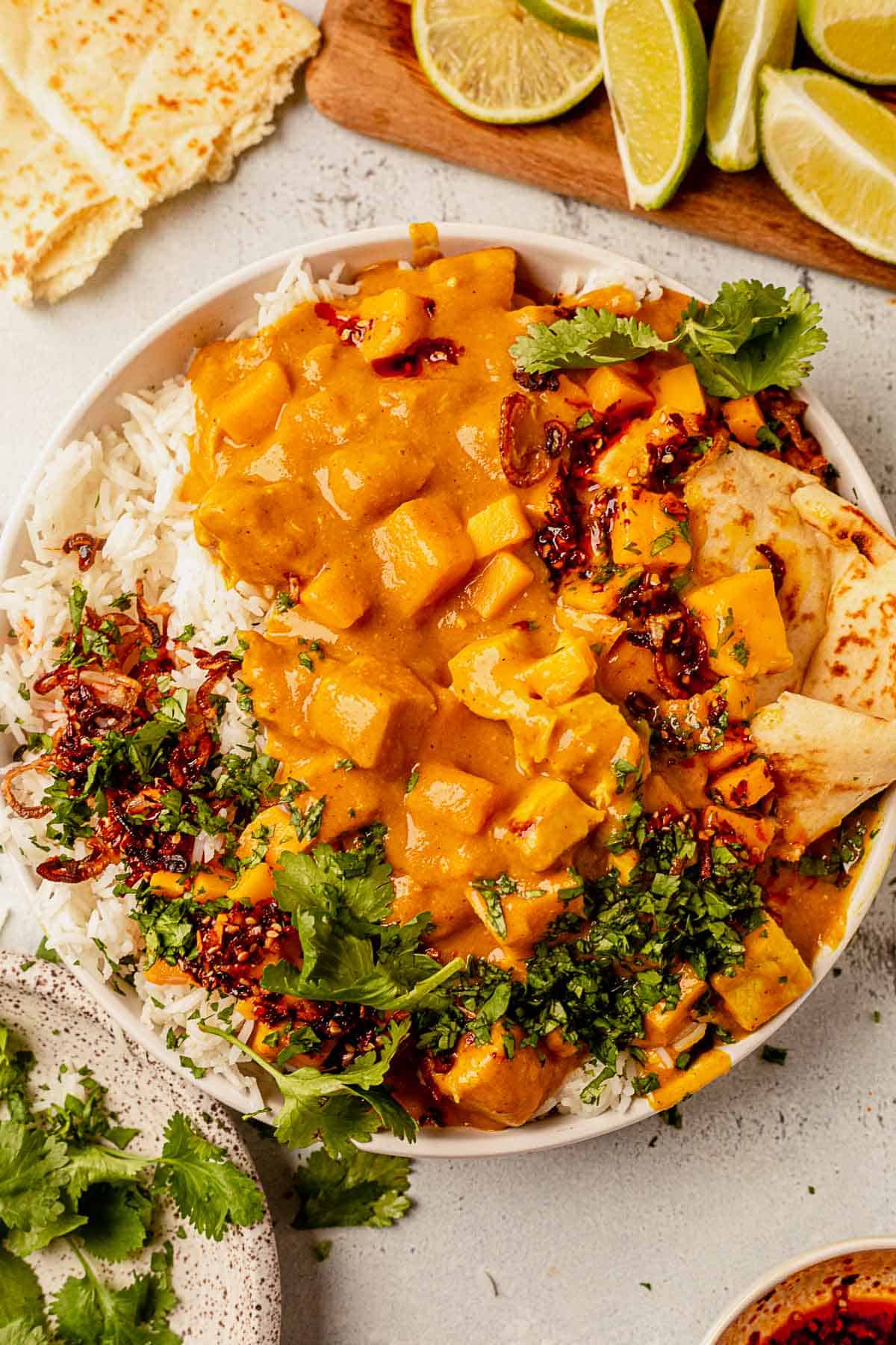 mango chicken curry on top of rice with cilantro and naan