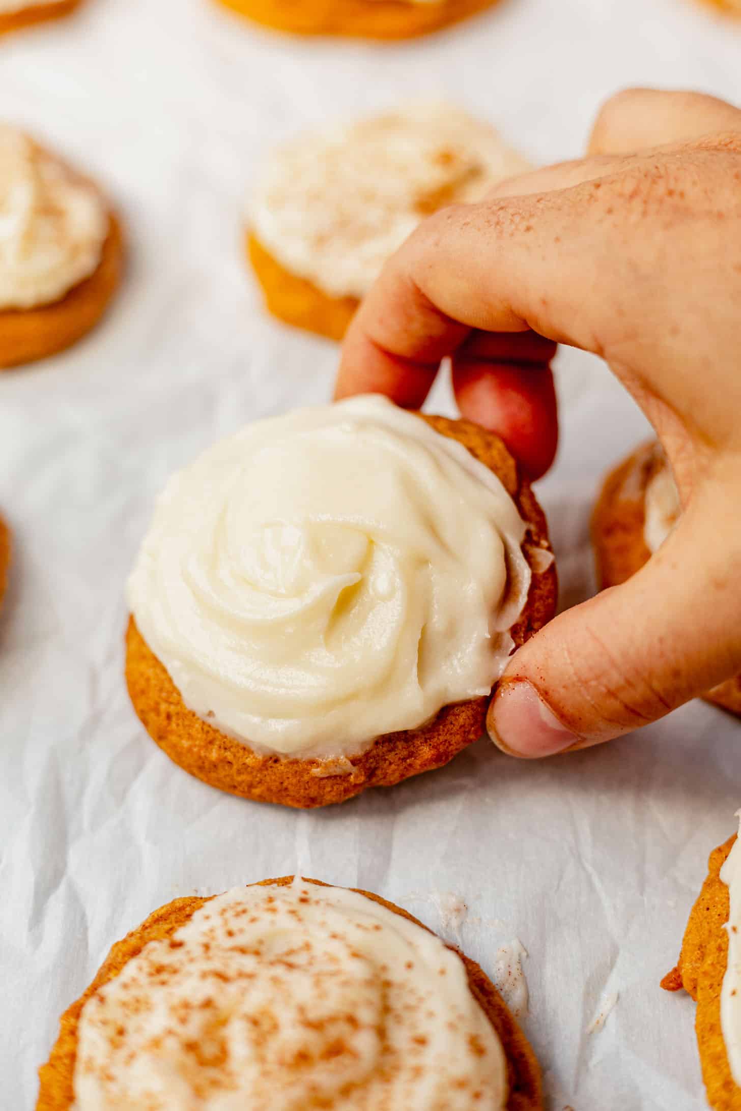 picking up a soft pumpkin cookie with cream cheese frosting